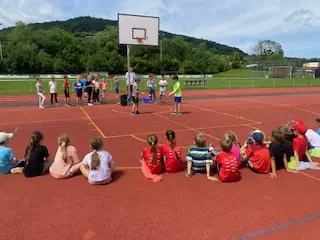 Kinder sitzen auf dem Sportplatz