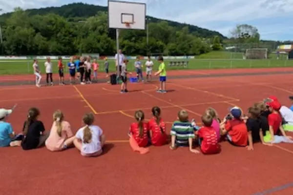 Kinder sitzen auf dem Sportplatz